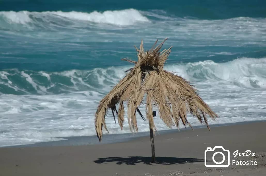 Sonnenschirm aus Palmenblättern an Strand in Kreta